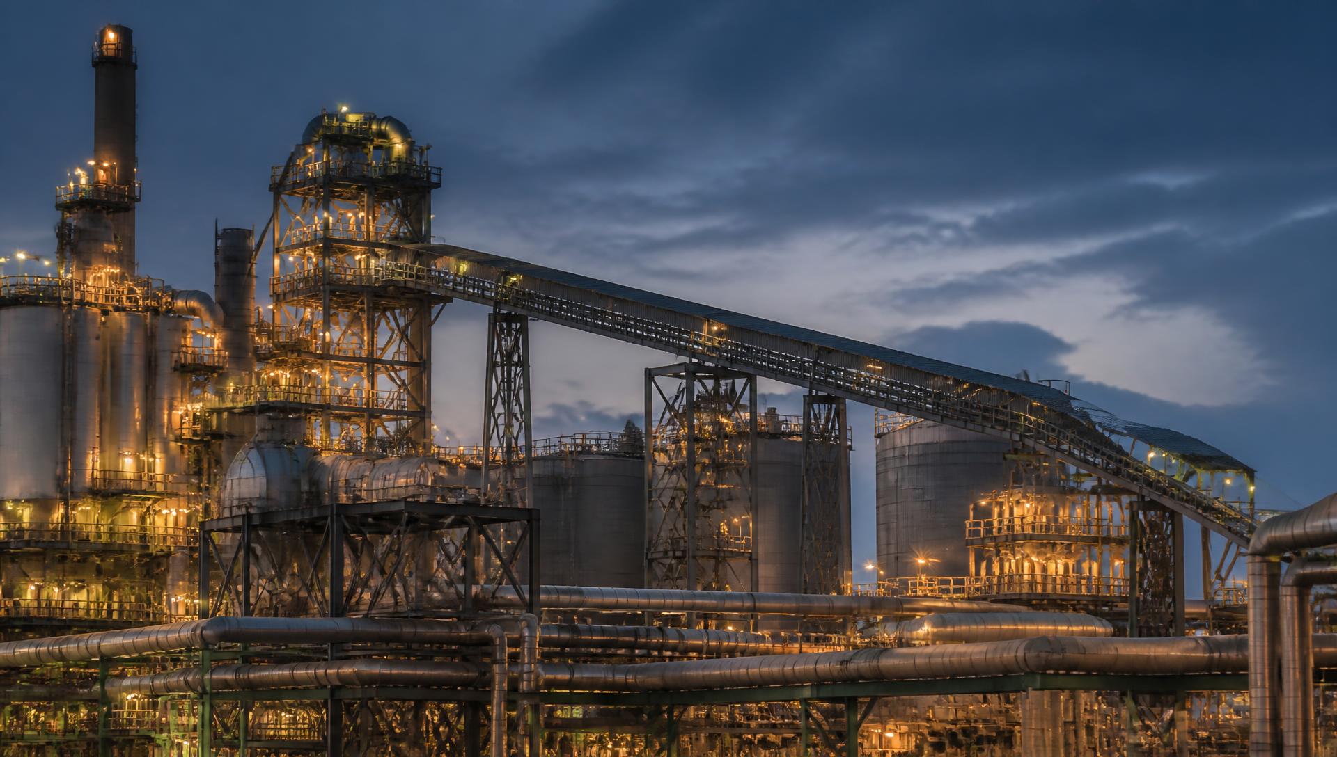 Industrial processing plant with structural steel and piping at dusk